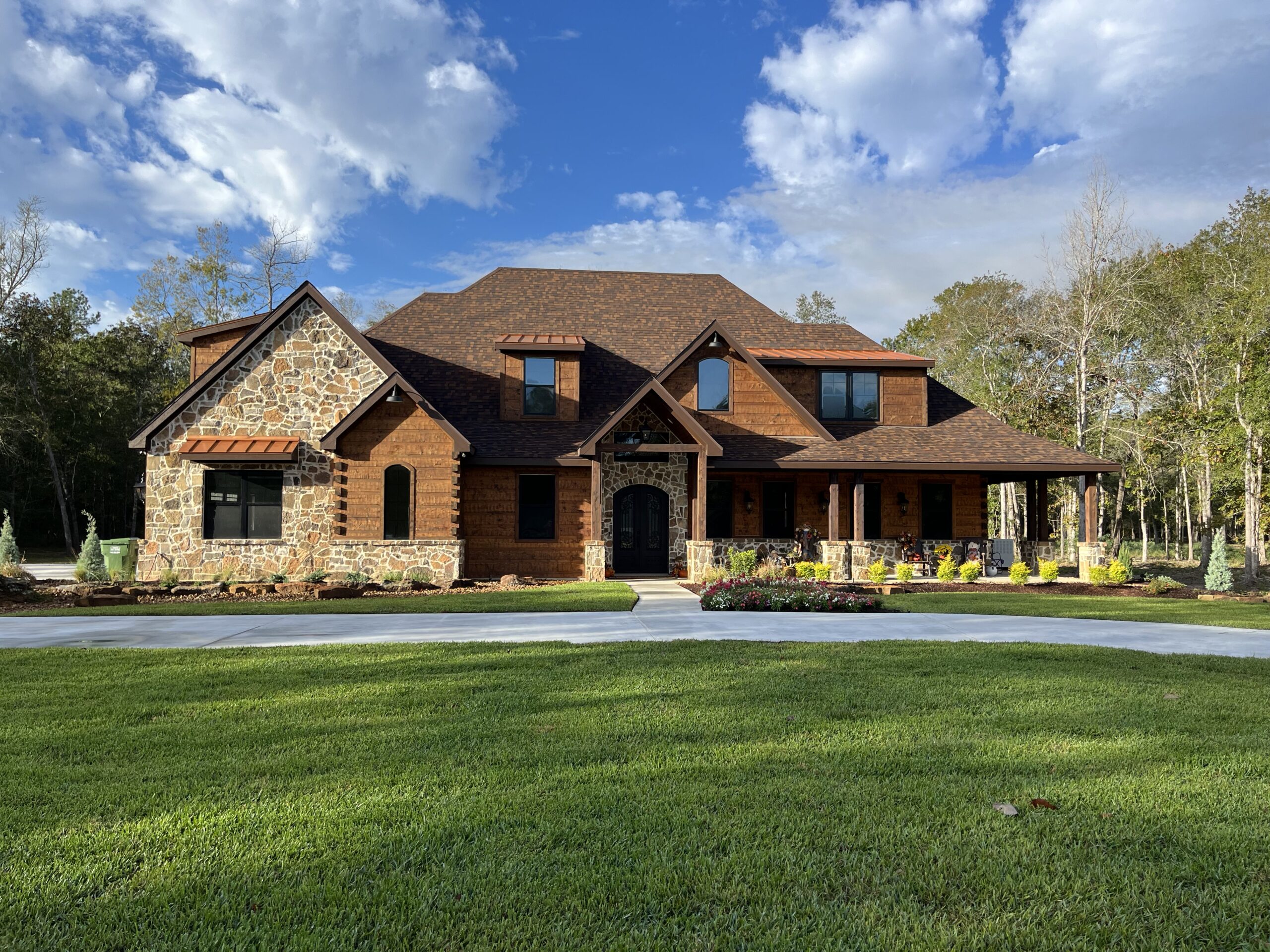 Mountain-Style Home in Dayton, TX. Mix of earth tones in stone, roofing, and log siding.