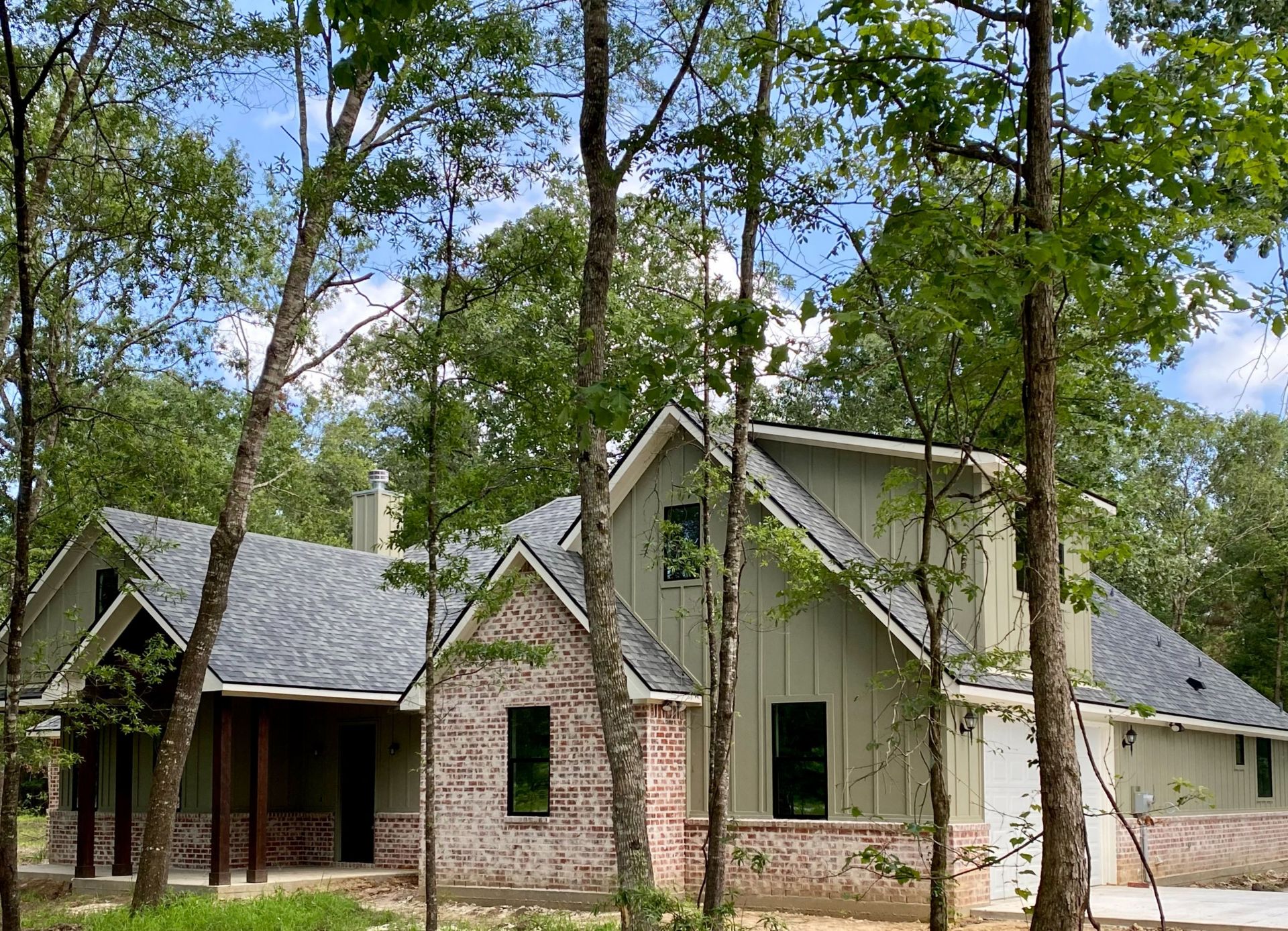 Custom Home withLight Green board & batten siding and a red brick skirt.